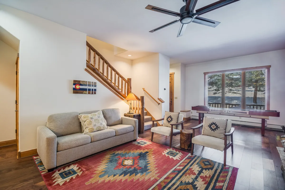 This inviting living area features a plush sofa, a soft rug, and ample natural light streaming through a large window. The scene suggests a versatile space perfect for unwinding after a day outdoors or gathering with friends for evening entertainment.