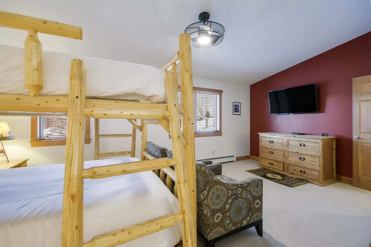 A multi-functional room with a bunk bed, sofa, and a TV, this space is set up for watching movies, playing games, or simply relaxing after an active day. The layout encourages group interaction and leisure.